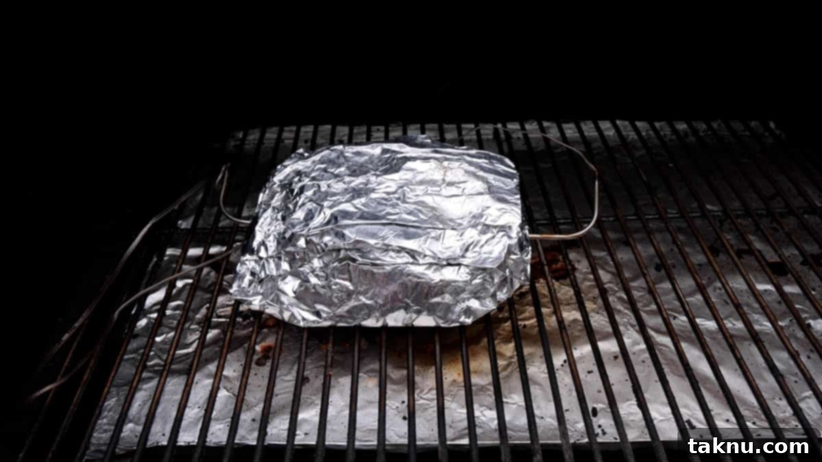 Slow-Smoked Corned Beef 8 Foil-wrapped corned beef brisket resting on a grill grate, ready for the final tenderizing phase.