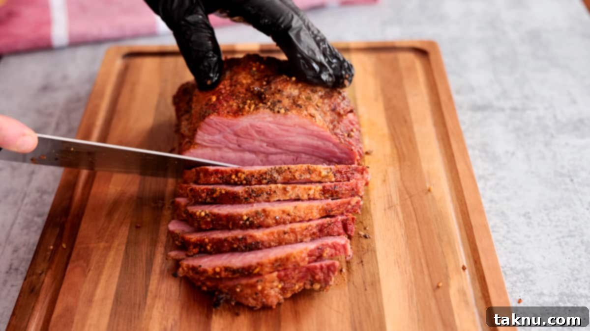 Slow-Smoked Corned Beef 9 Expertly sliced smoked corned beef on a wooden cutting board, being cut against the grain with a sharp knife.