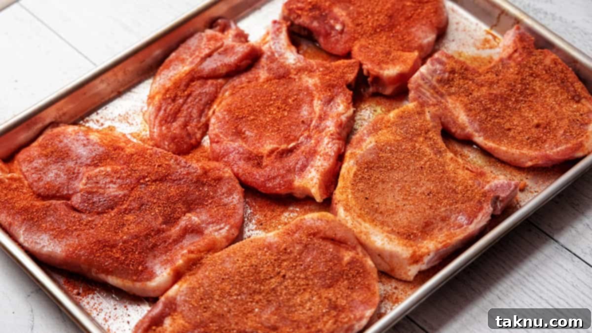 Perfect Traeger Pork Chops 6 Six seasoned pork chops arranged neatly on a baking tray, ready to be smoked or cooked.