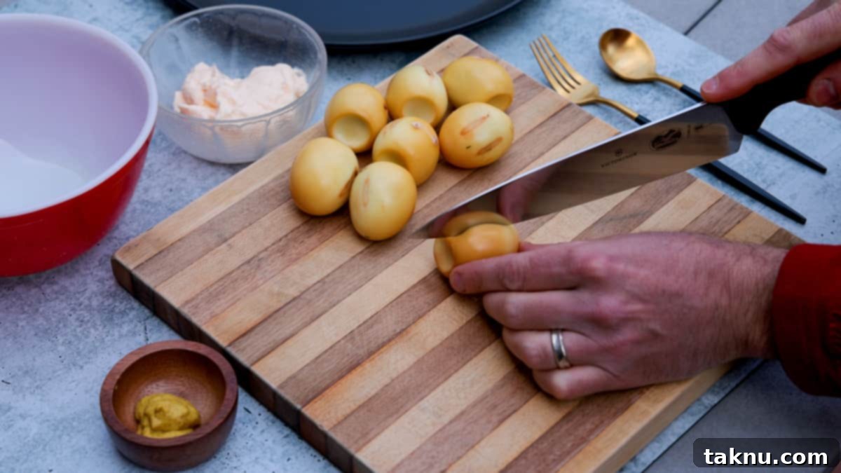 Smoky Deviled Delights 3 Slicing smoked eggs in half on cutting board with small dishes of mayonnaise and mustard nearby.