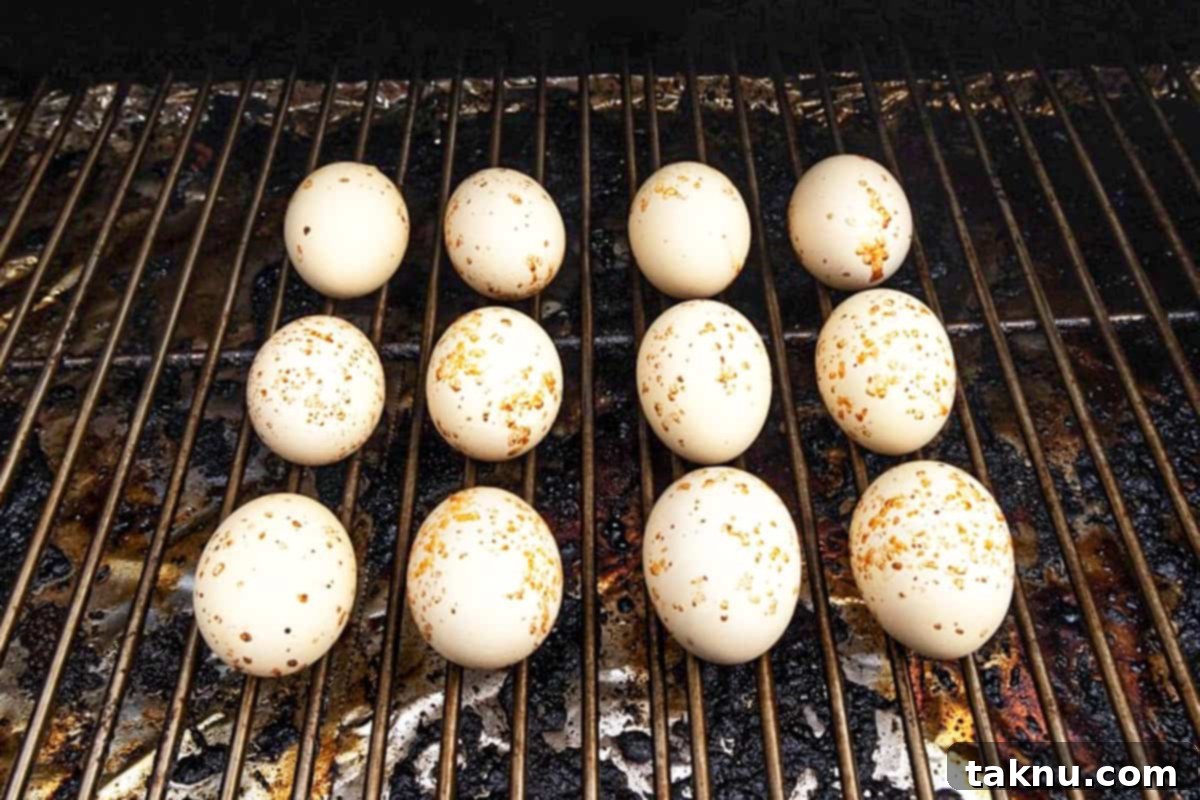 Twelve eggs on grill, smoking until fully cooked, displaying a slight smoky tint on the shells.