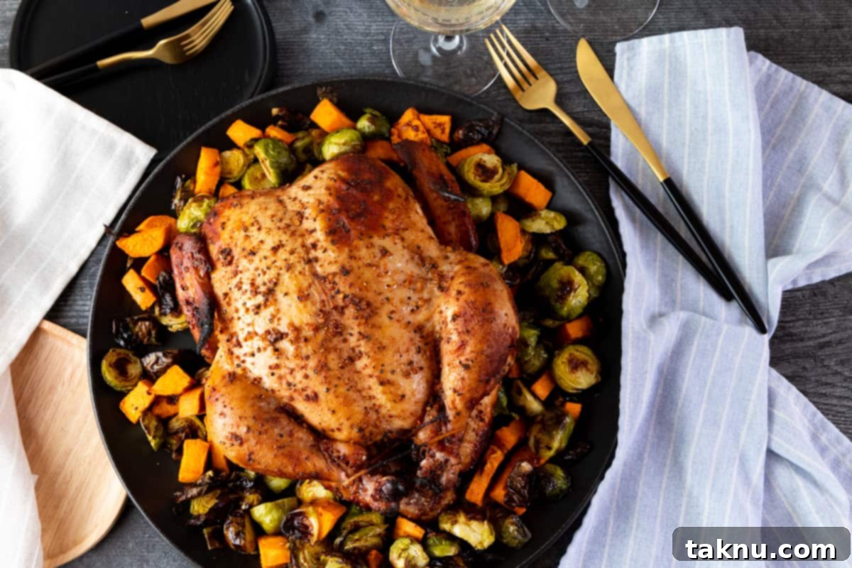 Traeger Smoked Buttermilk Chicken 10 Whole cooked chicken on platter with vegetables surrounded by blue napkins and cutlery.