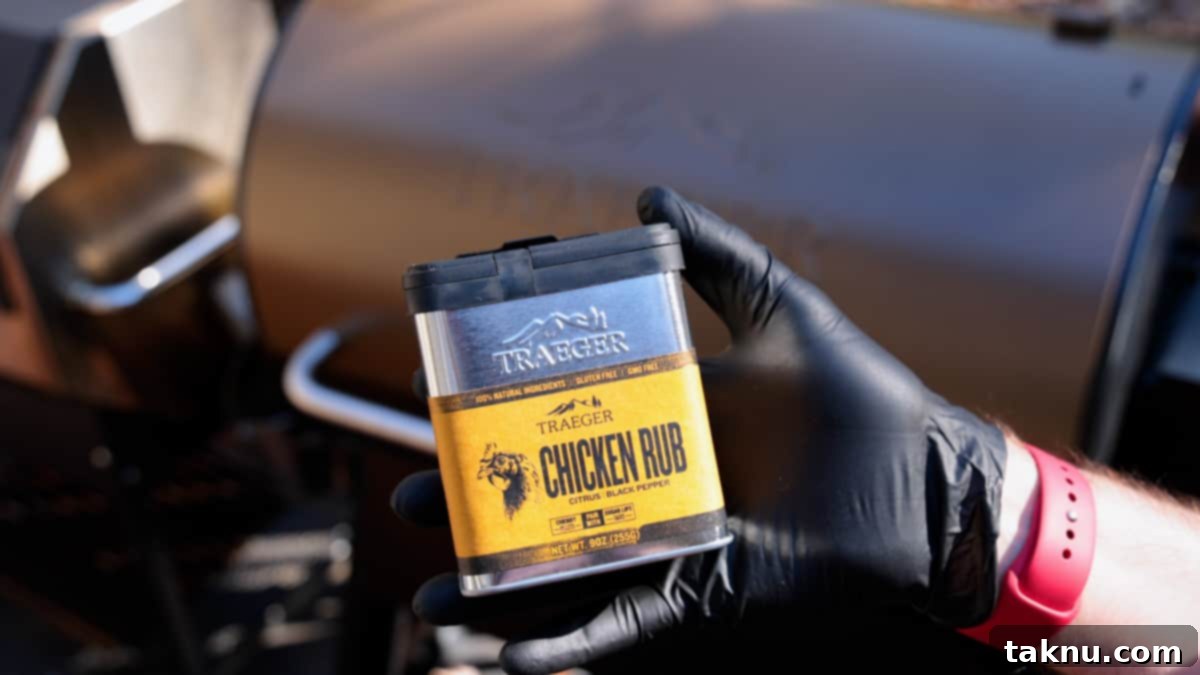 Traeger Smoked Buttermilk Chicken 5 Hand wearing a black glove applying Traeger chicken rub generously onto a chicken.