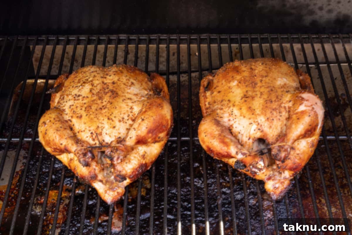 Traeger Smoked Buttermilk Chicken 6 Two whole chickens cooking on a Traeger grill, infusing with smoke.