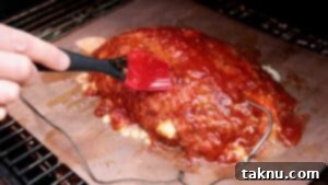 Brushing on pineapple glaze onto meatloaf with a red tipped brush, creating a delicious crust.