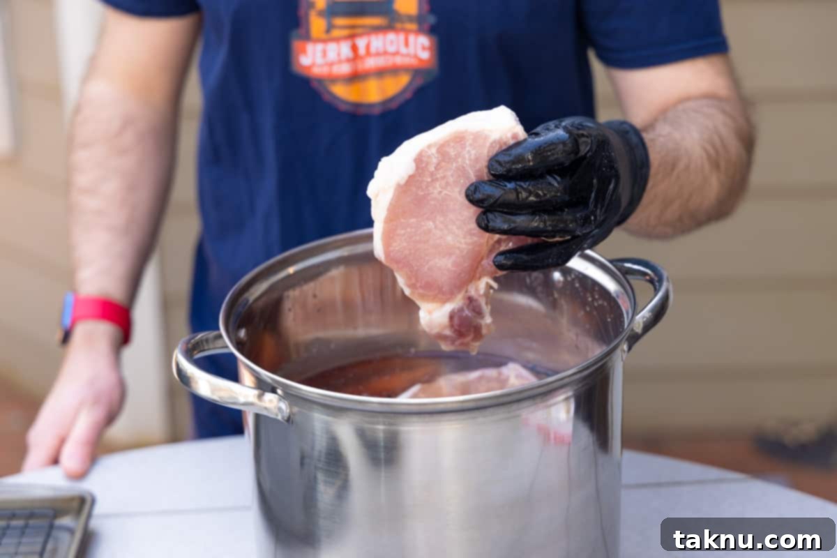 Smoky Pork Chops with Sweet Apple Glaze 4 Man carefully removing plump pork chops from a large silver pot filled with brining liquid, preparing them for the next stage of cooking.