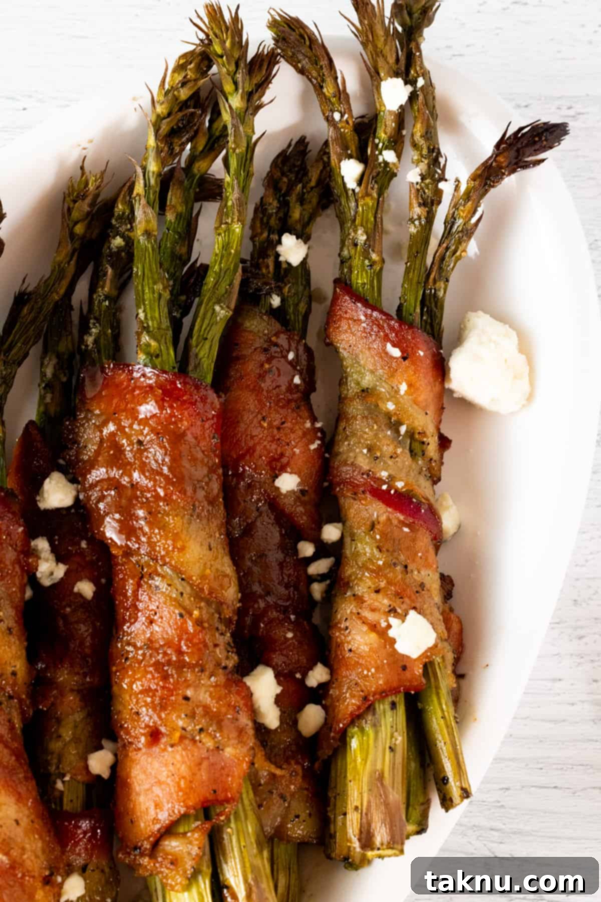 Smoked Bacon Wrapped Asparagus 2 Asparagus wrapped in bacon on white plate.