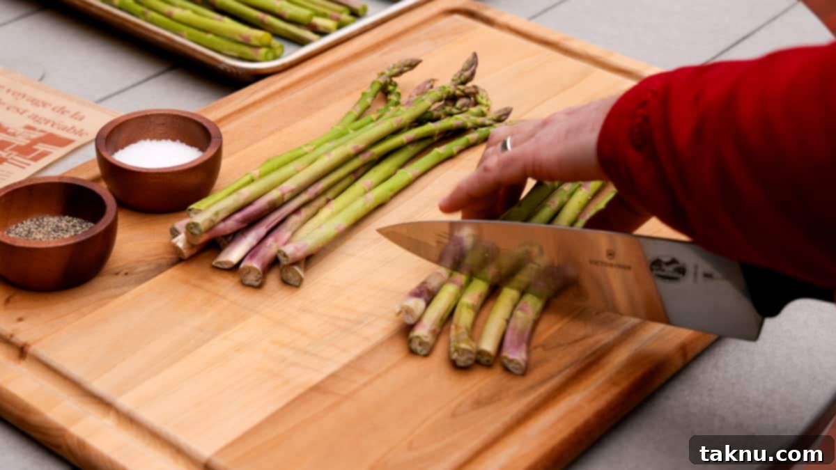 Smoked Bacon Wrapped Asparagus 4 Cutting the ends off asparagus with a knife atop a wood cutting board.