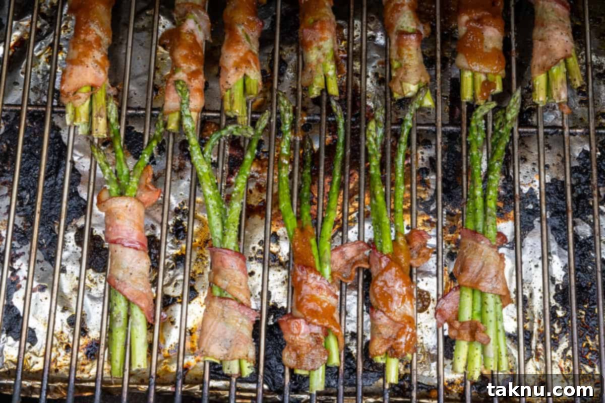 Smoked Bacon Wrapped Asparagus 6 Grilled bacon wrapped asparagus on grill grates.
