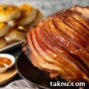 Sizzling Christmas BBQ Recipes 8 Spiral ham on black plate with biscuits and jam in background.