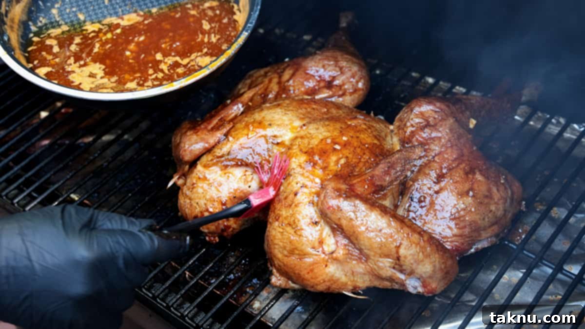 Fiery Sriracha Smoked Spatchcock Turkey 8 Applying sriracha glaze to turkey with red brush while turkey is on grill rack of smoker.