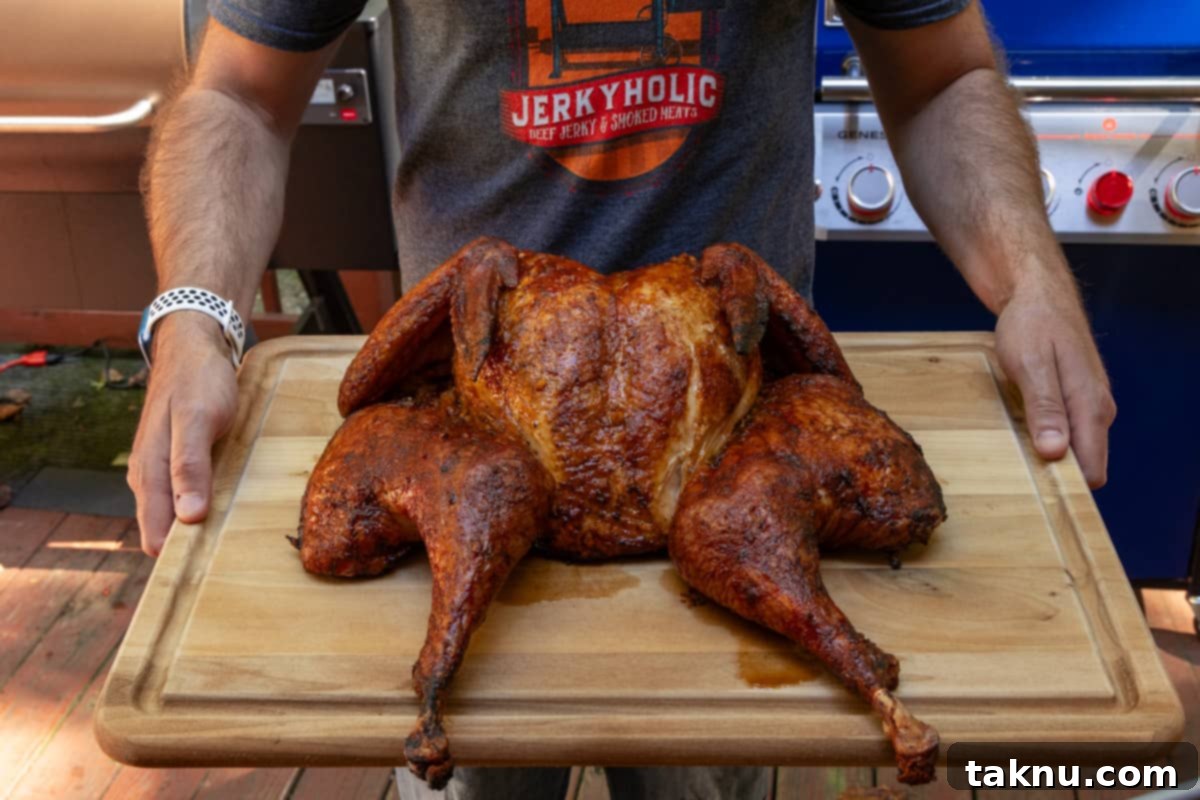 Fiery Sriracha Smoked Spatchcock Turkey 9 Spatchcock turkey on cutting board after cooking being held by man wearing a jerkyholic t shirt.
