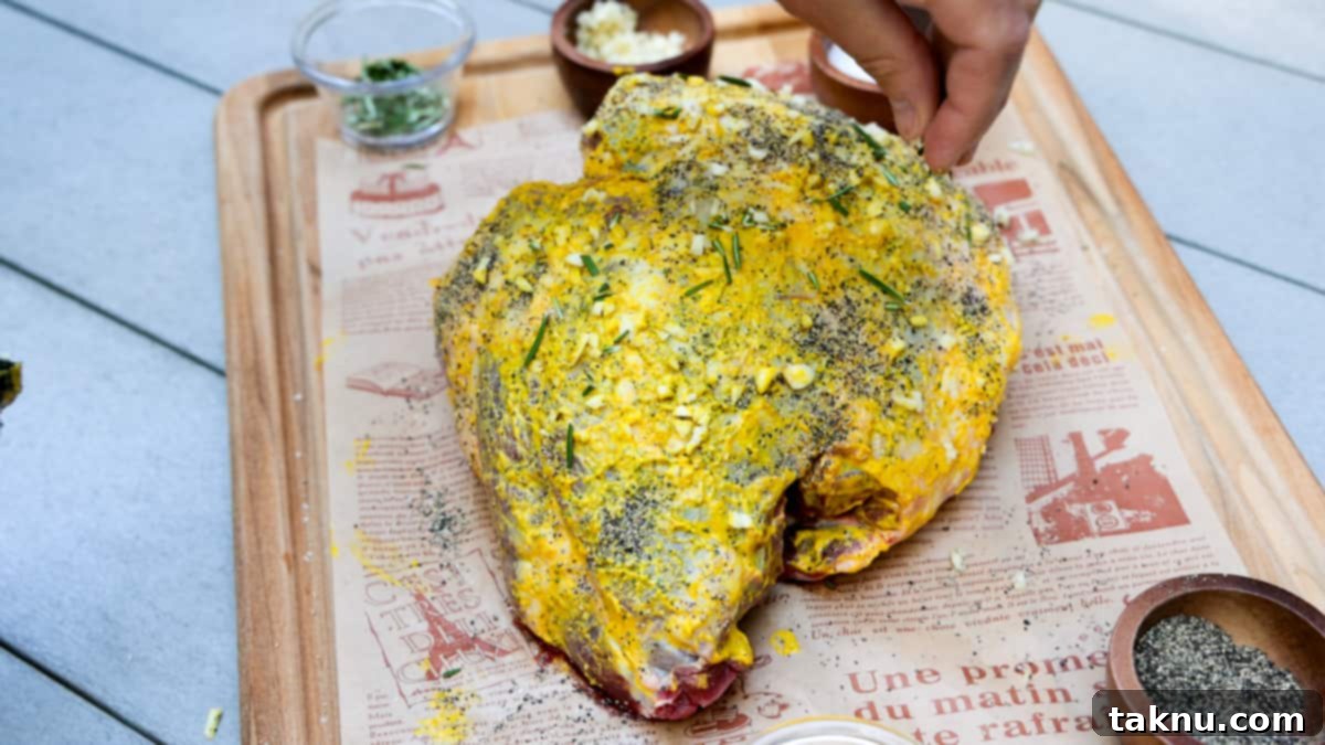 Seasoned leg of lamb on cutting board atop table. 