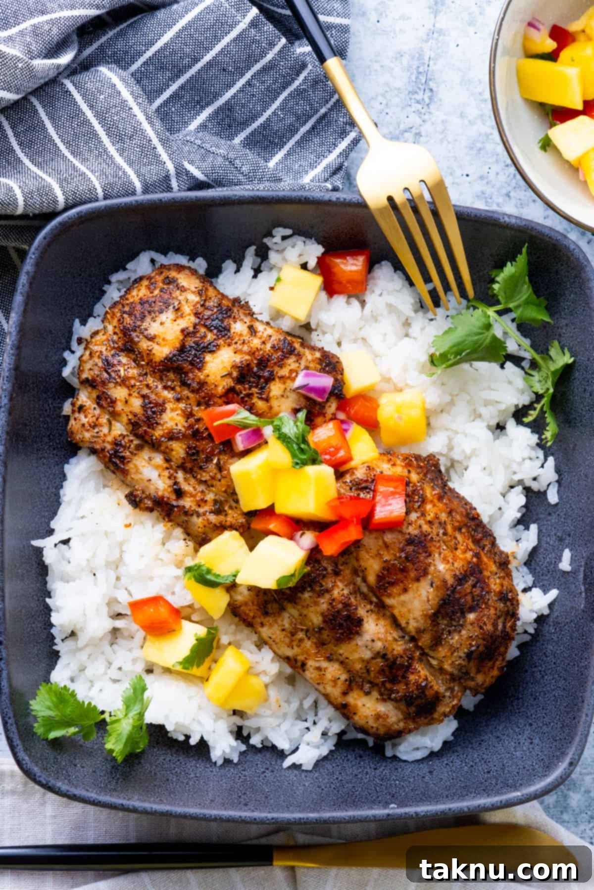 Two perfectly grilled Mahi Mahi fillets atop a bed of white rice, served with a fork.