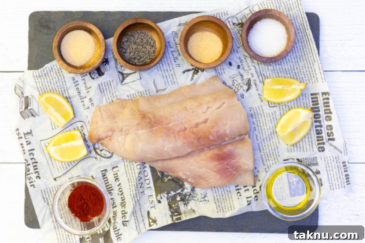 Fresh dolphin fish fillet on newspaper surrounded by small bowls of spices ready for seasoning.