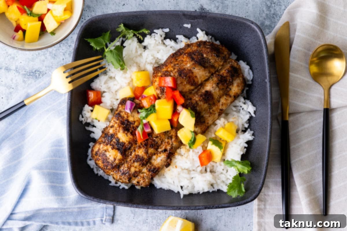 Mahi Mahi fillet served atop a bed of white rice and topped with fresh mango salsa, presented in a blue square bowl.