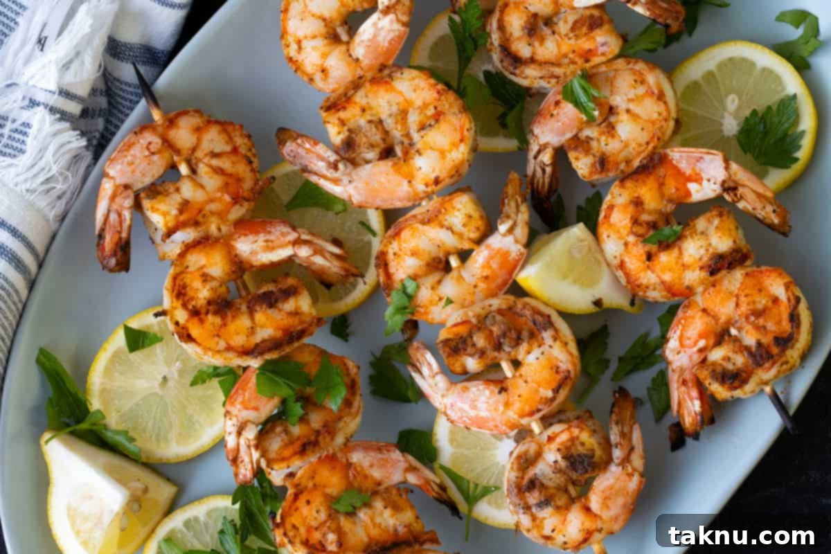 Grilled shrimp skewers artfully arranged on a white plate, garnished with vibrant lemon wedges and fresh parsley.