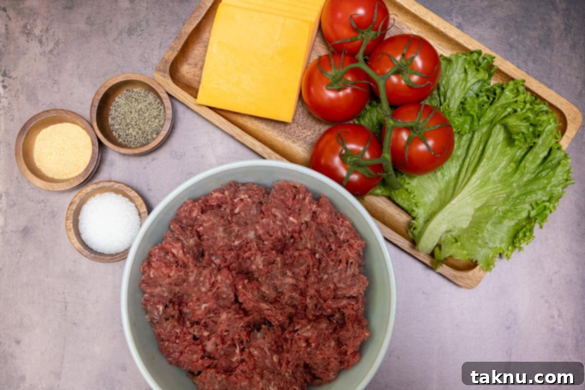 Bowl of bison ground meat with a tray of lettuce, cheese, and tomatoes accompanied by small wooden bowls of salt, pepper, garlic powder.