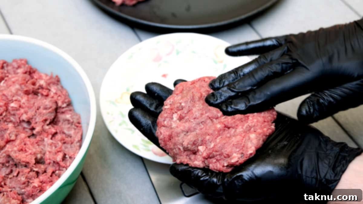 Forming bison burger patties of ground meat with hands with black gloves.