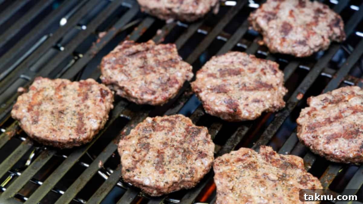 Eight bison burger patties cooking on grill.