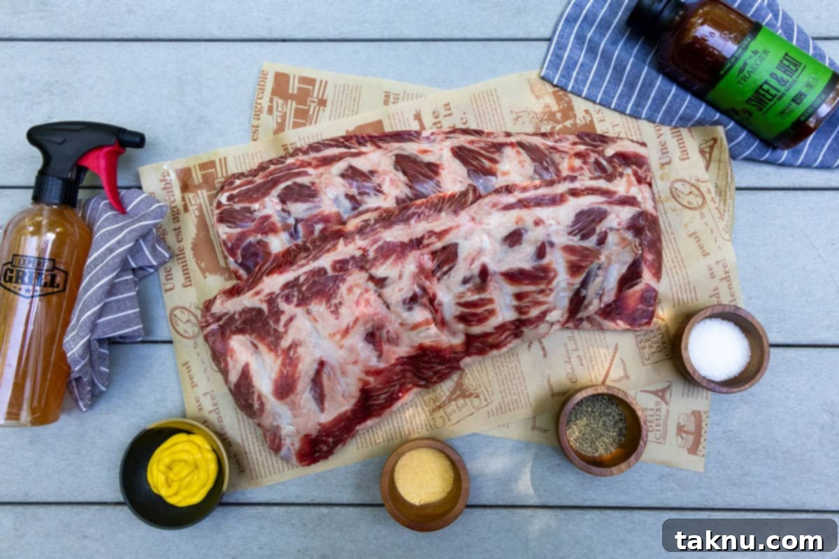 Two racks of ribs on cutting board with seasonings in dishes, bbq sauce, & spray bottle with apple cider vinegar.