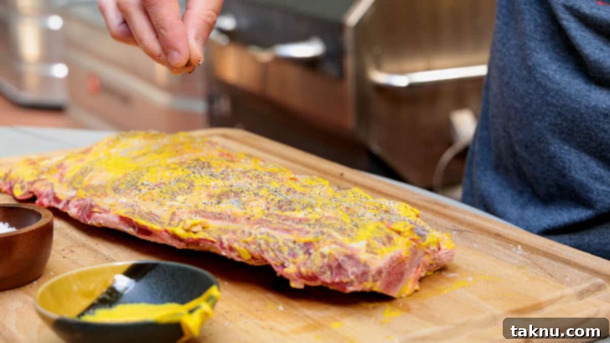 Seasoning beef ribs atop a cutting board with salt, pepper, garlic by hand.