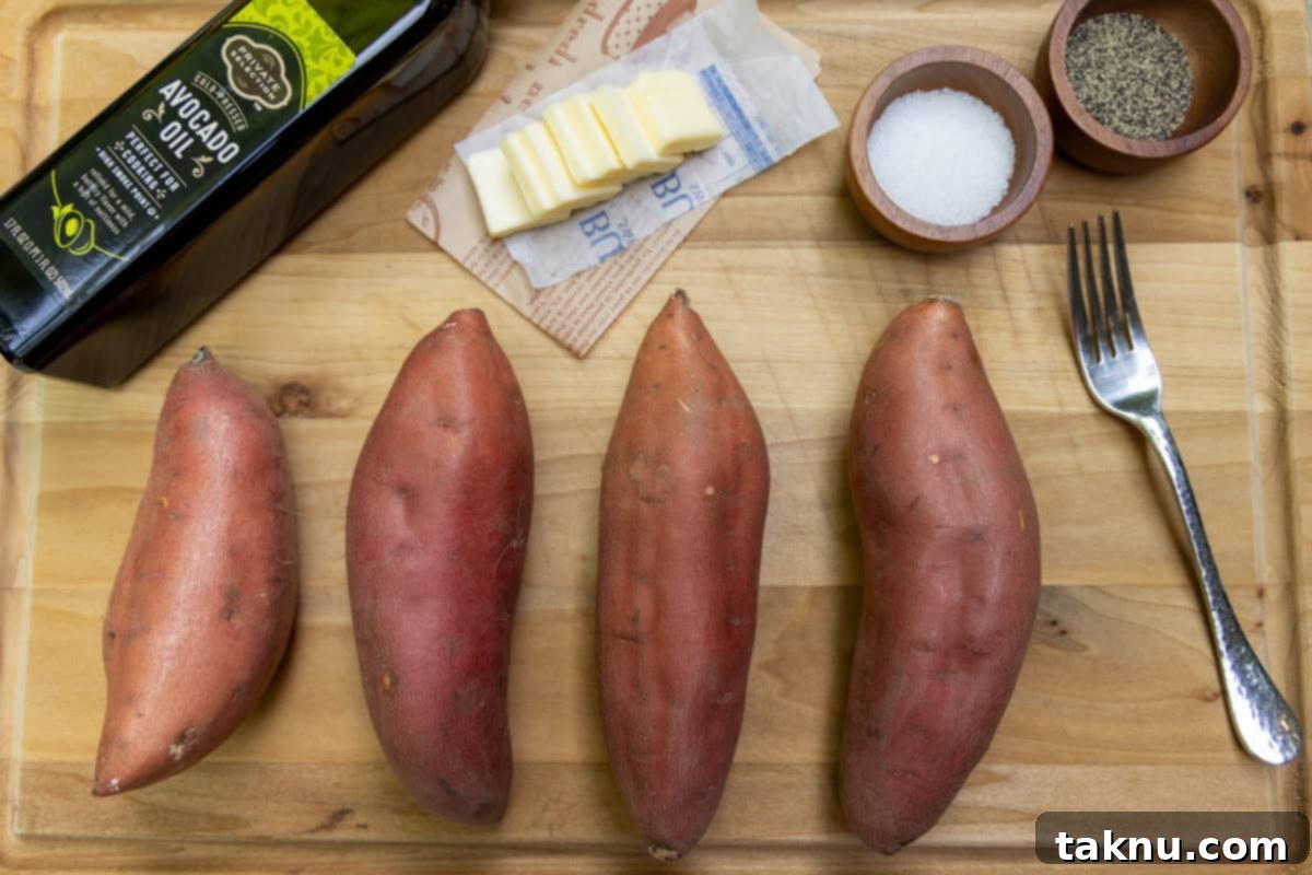 Four sweet potatoes on wood cutting board with a bottle of oil, butter, salt, and pepper in dishes.
