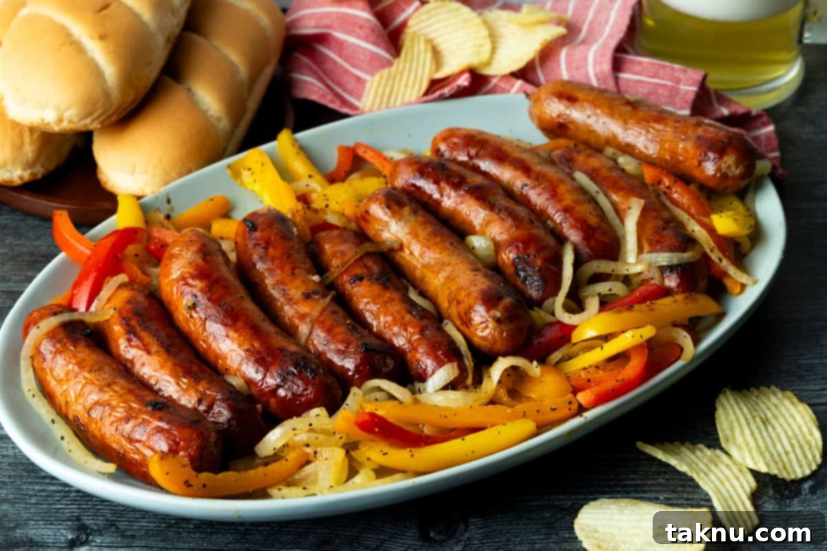 Savory Sausage and Roasted Peppers 13 Grilled sausage atop onions and peppers on blue platter with buns and potato chips in background.