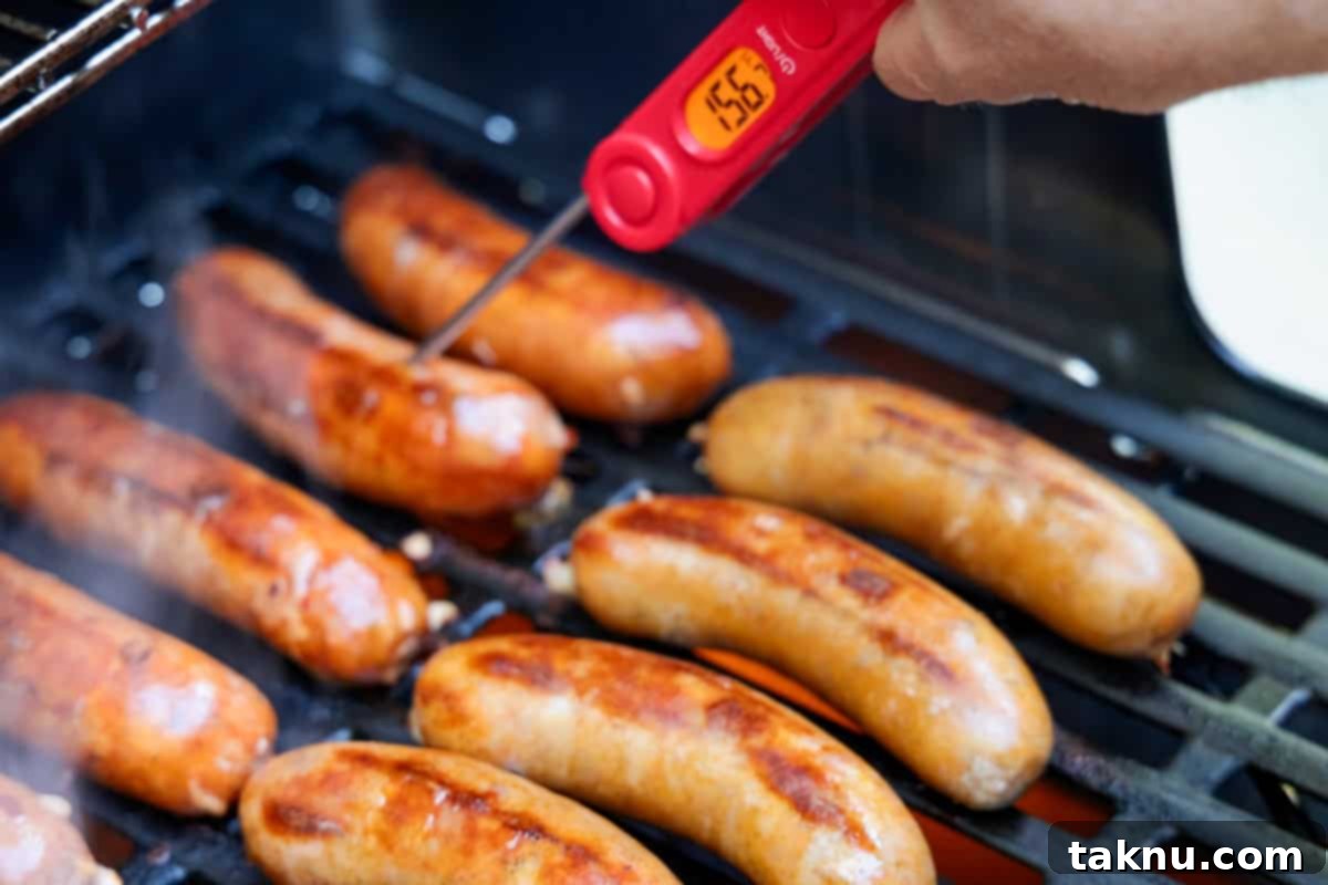 Savory Sausage and Roasted Peppers 8 Checking temperature of sausages on grill with a red meat thermometer showing 156 degrees f.