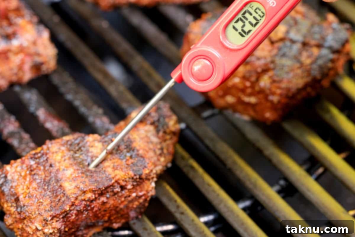 A digital meat thermometer inserted into a grilling steak, clearly showing an internal temperature of 120°F, indicating it's ready for resting.