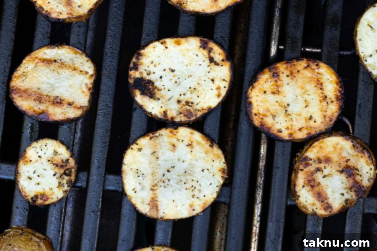 Six thinly sliced potatoes grilling directly on the grates of a propane grill, spaced apart to prevent overlapping.