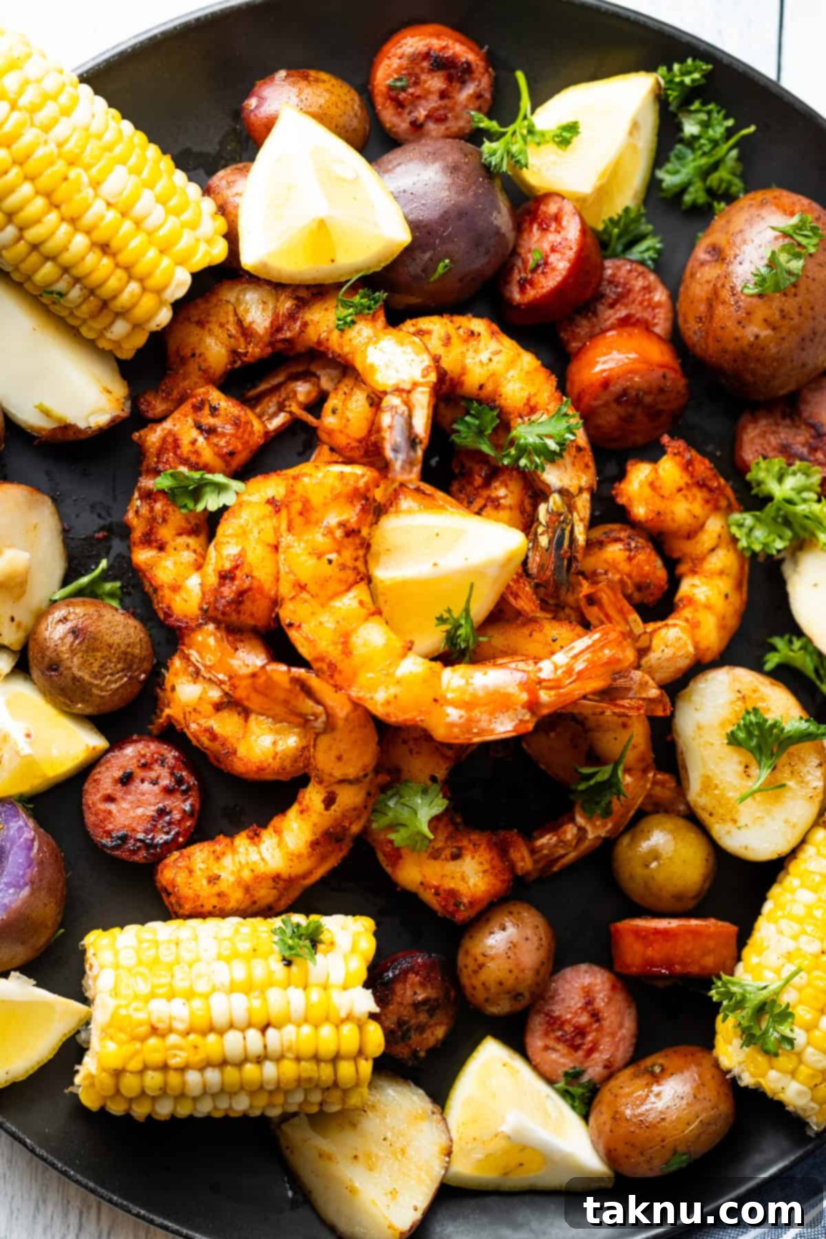 Succulent Smoked Shrimp 2 Smoked shrimp on a black plate surrounded by vibrant corn, tender potatoes, and bright lemon slices, showcasing a perfect summer meal.