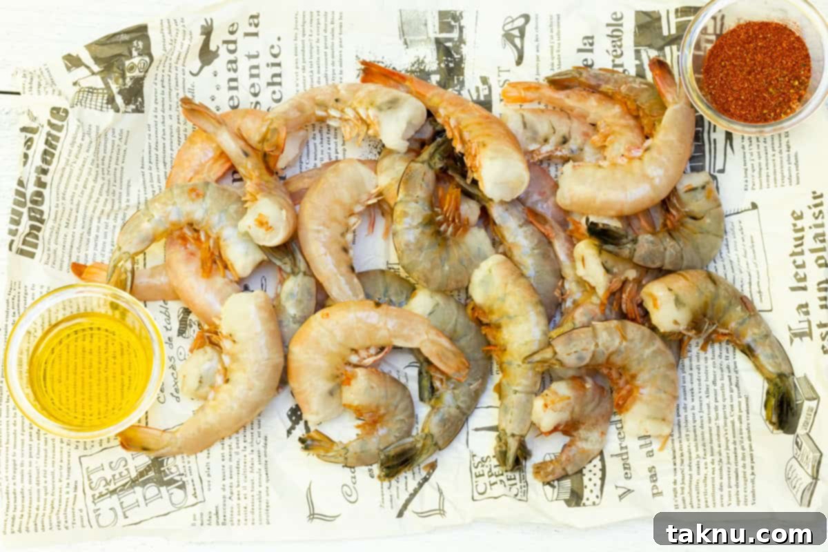 Succulent Smoked Shrimp 3 Uncooked shrimp laid out on newspaper, with a small dish of olive oil and a bowl of the spice blend ready for seasoning.