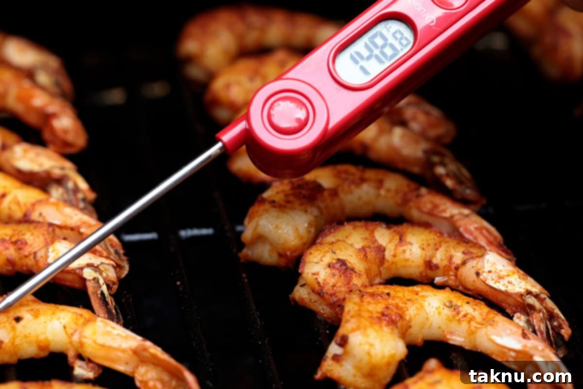 Succulent Smoked Shrimp 10 A digital meat thermometer accurately checking the internal temperature of a perfectly smoked shrimp on the grill.