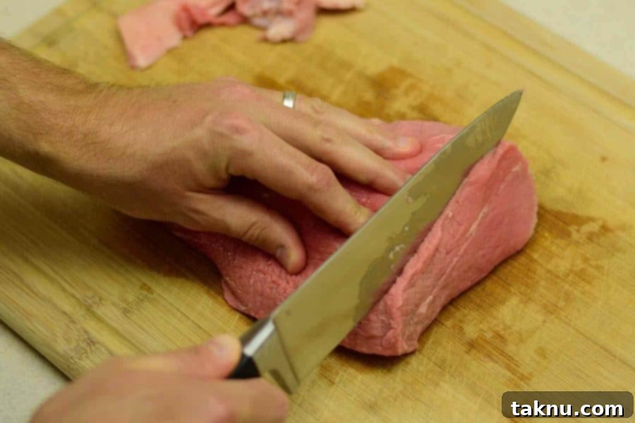 Crafting the Perfect Beef Jerky Marinade 4 Slicing meat for jerky on cutting board with sharp knife