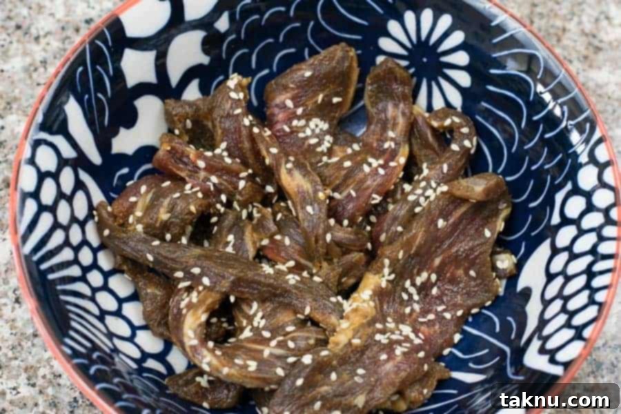 Marinated Korean BBQ Beef Jerky strips, ready for dehydration after soaking in flavorful sauce.