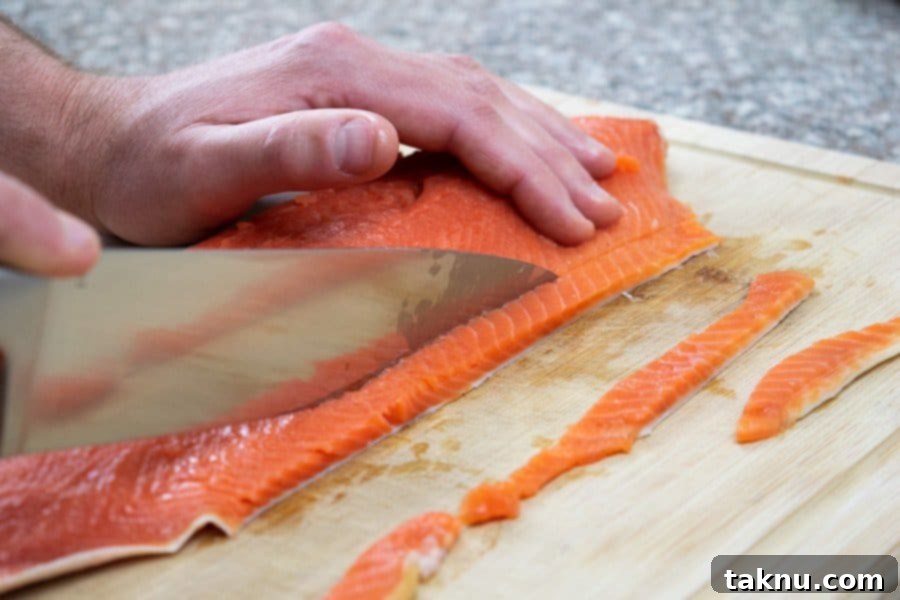 Slicing a salmon fillet lengthwise into thin strips for making jerky