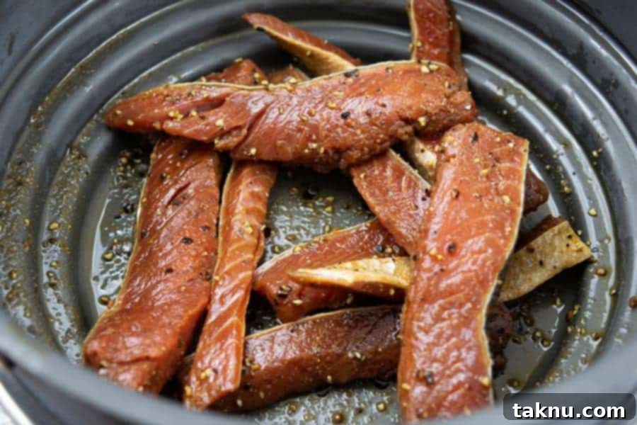 Salmon jerky strips soaking in a rich marinade in a ziplock bag