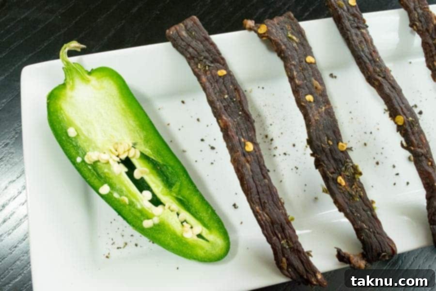 Perfectly finished South Texas Jalapeño Jerky on a white serving dish, garnished with fresh, halved jalapeños