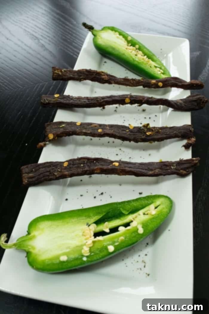 South Texas Jalapeño Beef Jerky slices with fresh jalapeños on a white dish