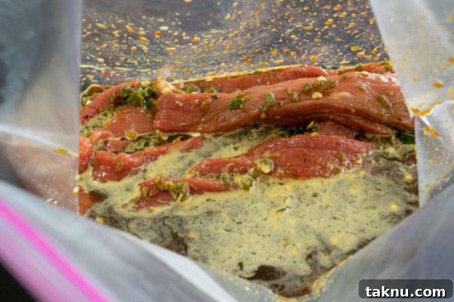 Jalapeño beef jerky strips submerged in a flavorful marinade within a sealed zip-lock bag, chilling in the fridge