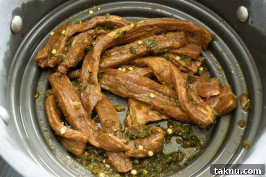 South Texas Jalapeño Jerky strips being strained in a colander, removing excess marinade before drying