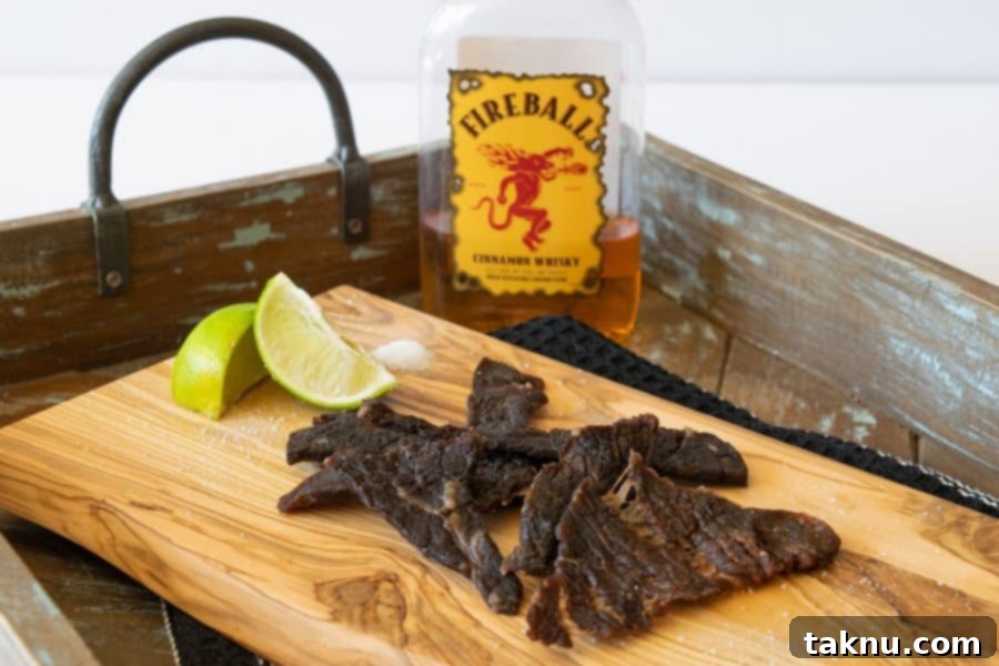 Fireball Whisky Infused Beef Jerky 2 Fireball whisky bottle behind beef jerky on cutting board with two lime wedges