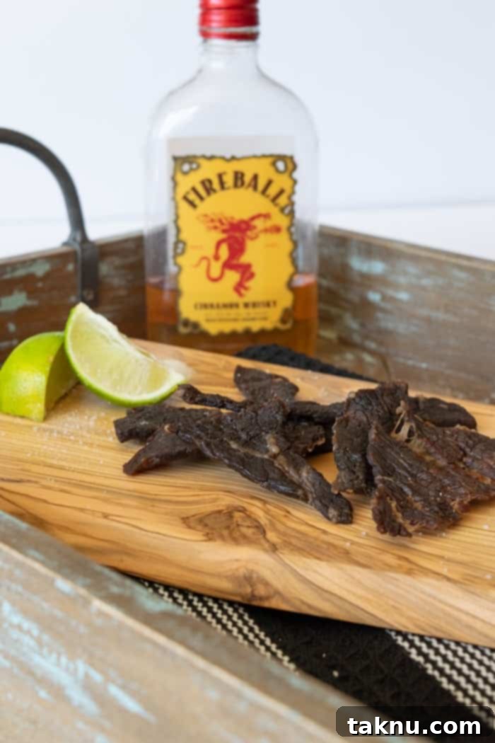 Fireball Whisky Infused Beef Jerky 6 Beef jerky on cutting board with lime wedges and a bottle of Fireball whisky