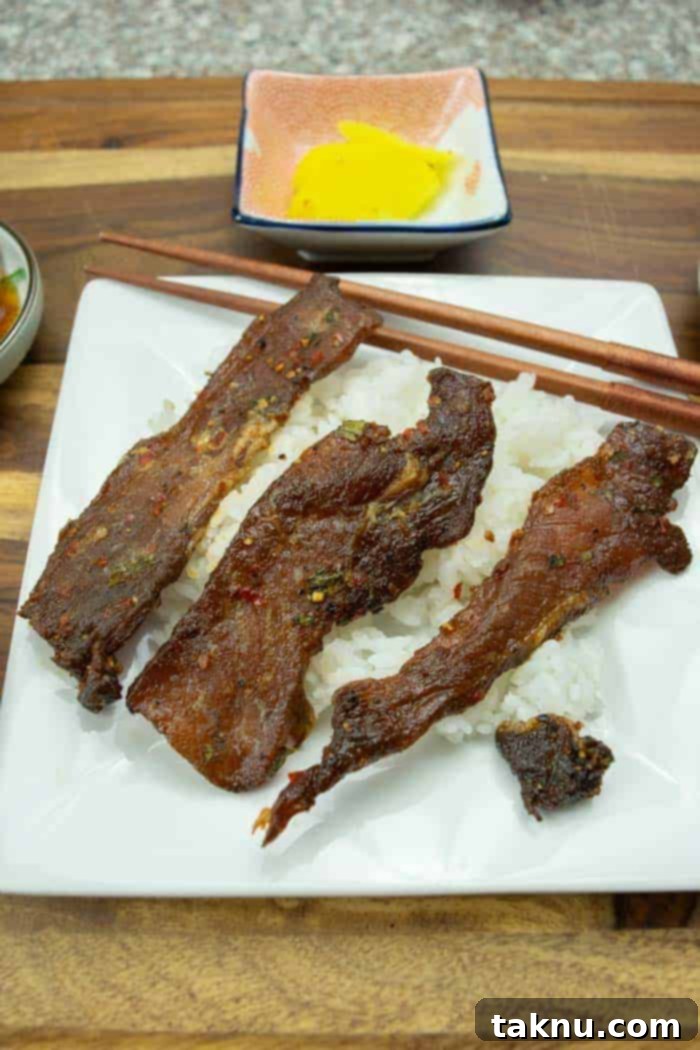 korean bbq pork jerky strips sitting on rice with chop sticks