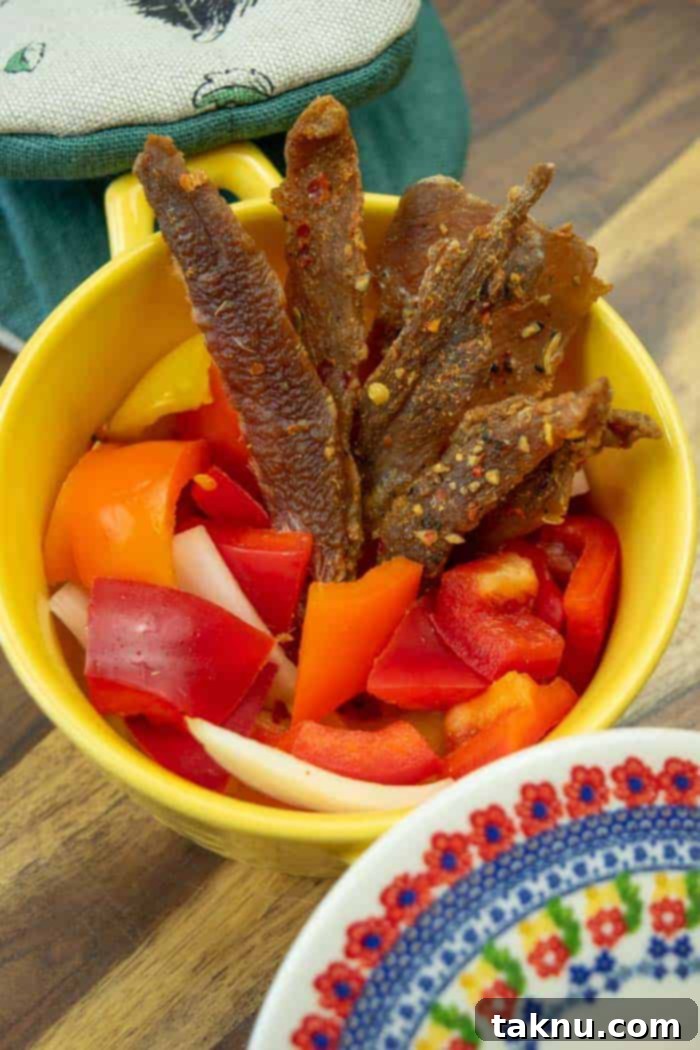 Italian pork jerky in yellow dish with pepper and onions