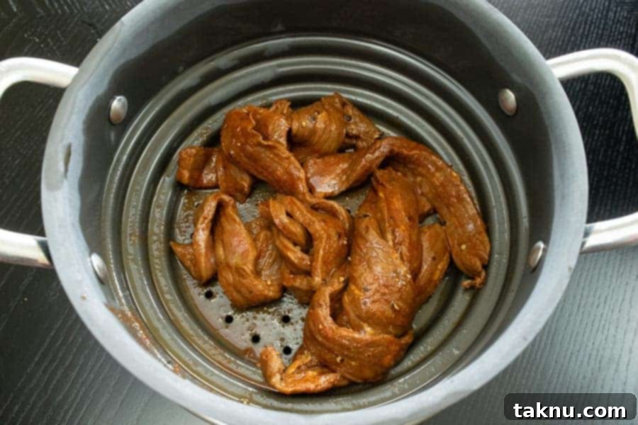 Habanero Tabasco beef jerky strips efficiently straining in a colander, removing excess marinade for optimal drying.