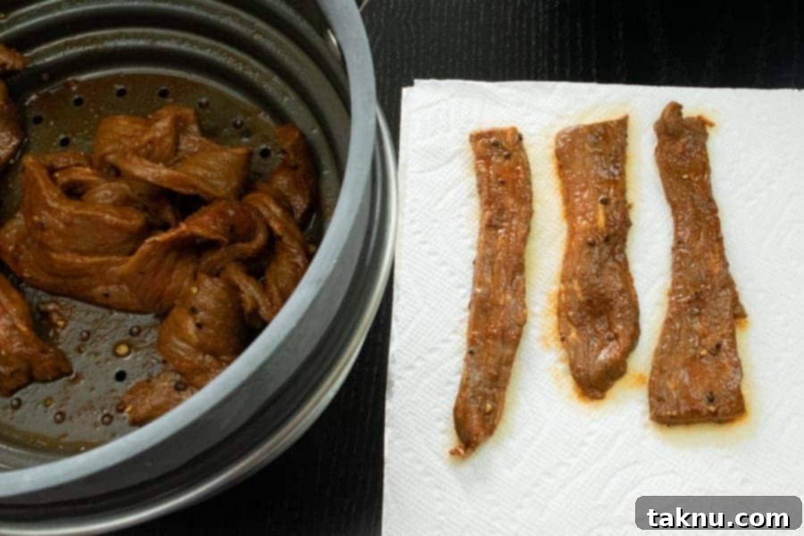 Habanero Tabasco jerky strips meticulously patted dry on paper towels, ensuring they are ready for efficient dehydration.