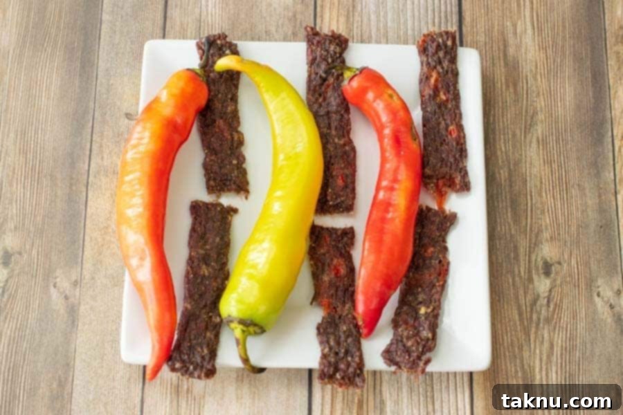 Wicked Fiery ground beef jerky on plate with banana peppers on wood background