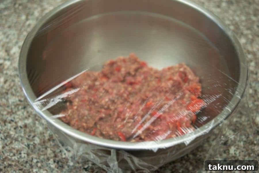 Wicked fiery ground beef jerky in bowl with plastic wrap over bowl